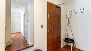 A hallway with a wooden door, a coat rack, and a mirror. - Bright Lambeth Apartment by Waterloo (London)