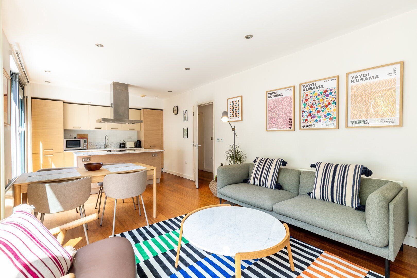 Una sala de estar moderna con un sofá, una mesa de comedor y una cocina al fondo.