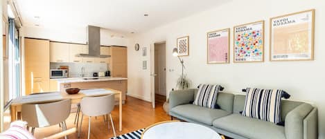 Una sala de estar moderna con un sofá, una mesa de comedor y una cocina al fondo.