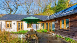 Een huis met een terras, een houten dek en een groene parasol.