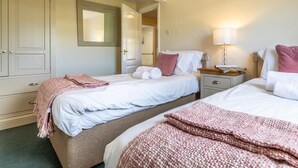 Ein Hotelzimmer mit zwei Betten, einem Kleiderschrank, einem Spiegel und einem Nachttisch mit Lampe.