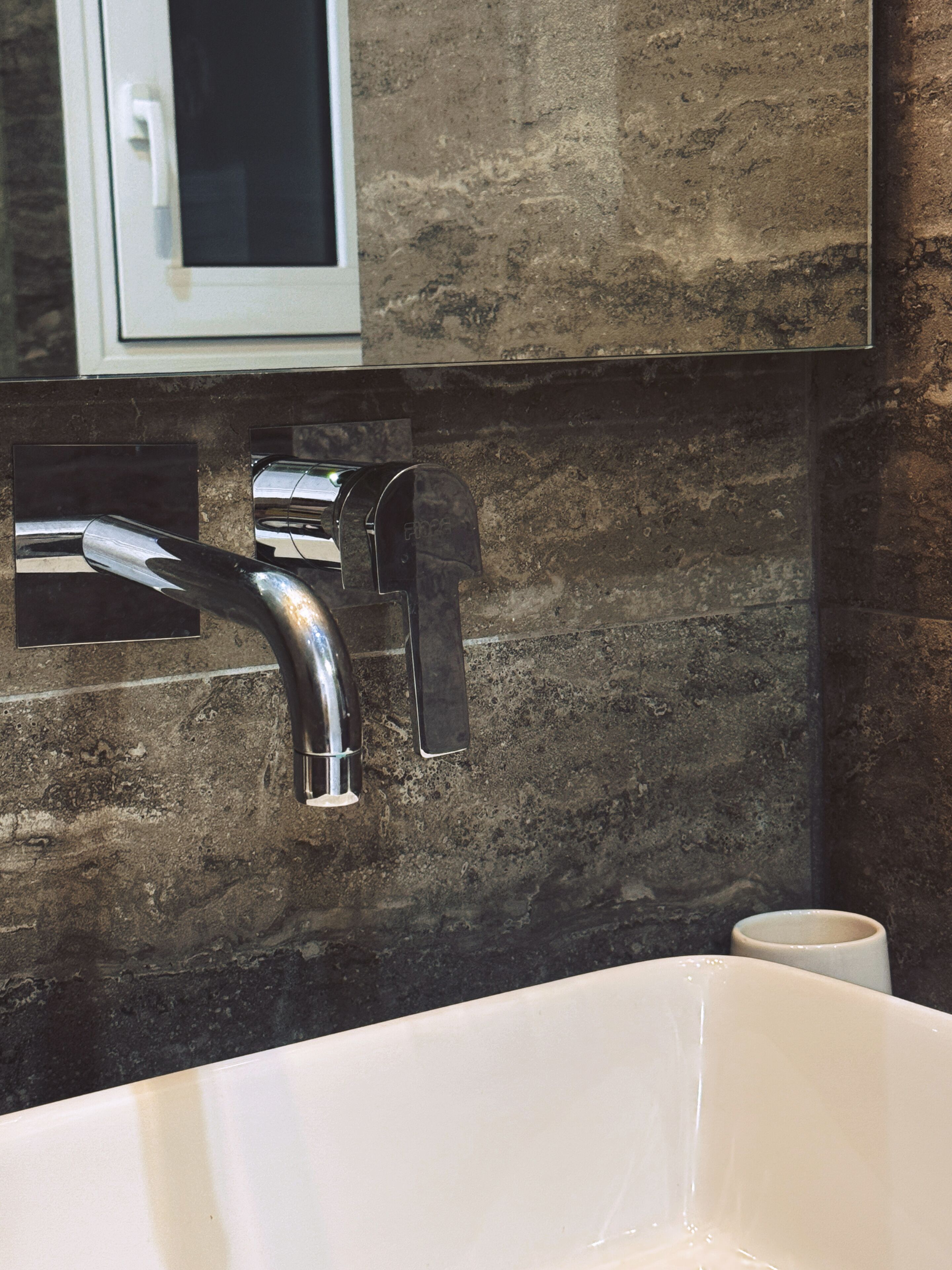 A bathroom with a white bathtub, a chrome faucet, and a textured wall.