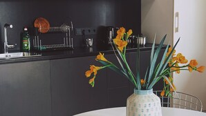 A modern kitchen with dark cabinets, a white dining table, and a vase with flowers.