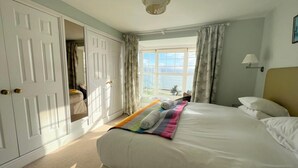 Una camera da letto con un letto, una finestra con vista e una porta che conduce in un'altra stanza.