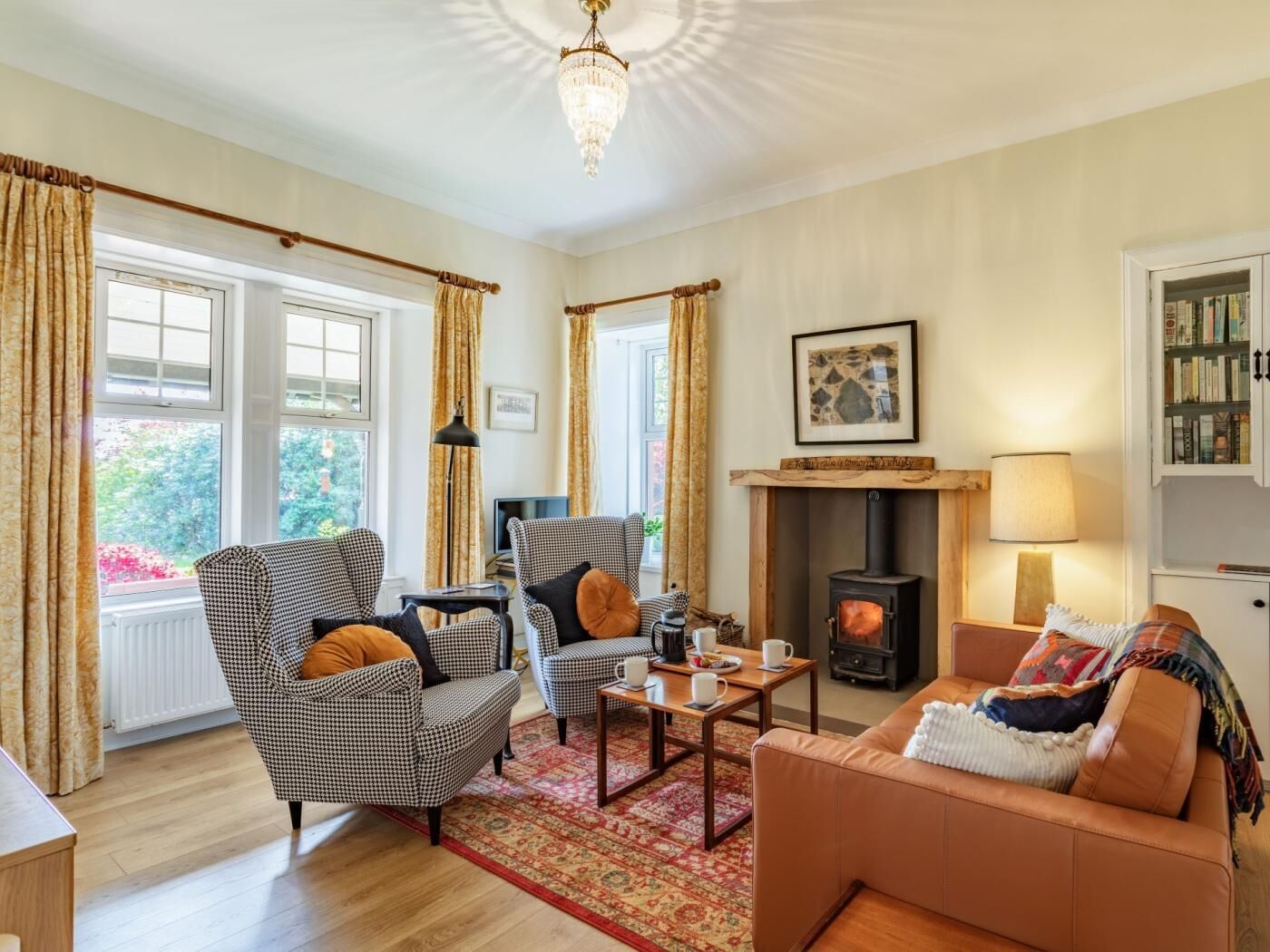A cozy living room with a fireplace, checkered armchairs, a sofa, and a coffee table.