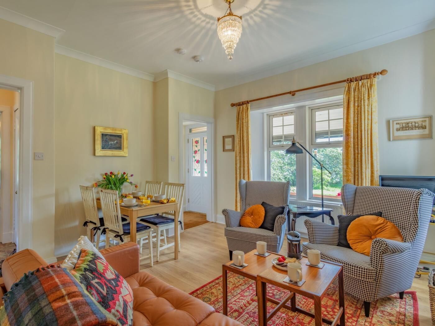 A living room with a sofa, armchairs, a coffee table, and a dining area with chairs and a table.