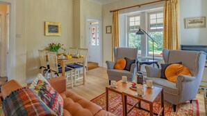 A living room with a sofa, armchairs, a coffee table, and a dining area with chairs and a table. - 2 Bed in Kirriemuir (oc-86235) (Logie)