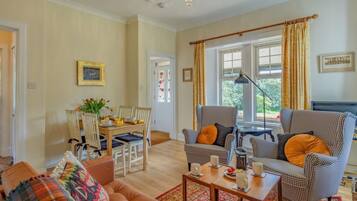 A living room with a sofa, armchairs, a coffee table, and a dining area with chairs and a table.