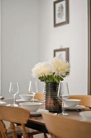 A dining table set with plates, bowls, and wine glasses, with a vase of flowers in the center. - Spacious London House for Groups, Free Parking (Greater London)