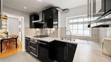 A modern kitchen with black cabinetry, a gas stove, a double oven, and a stainless steel sink.