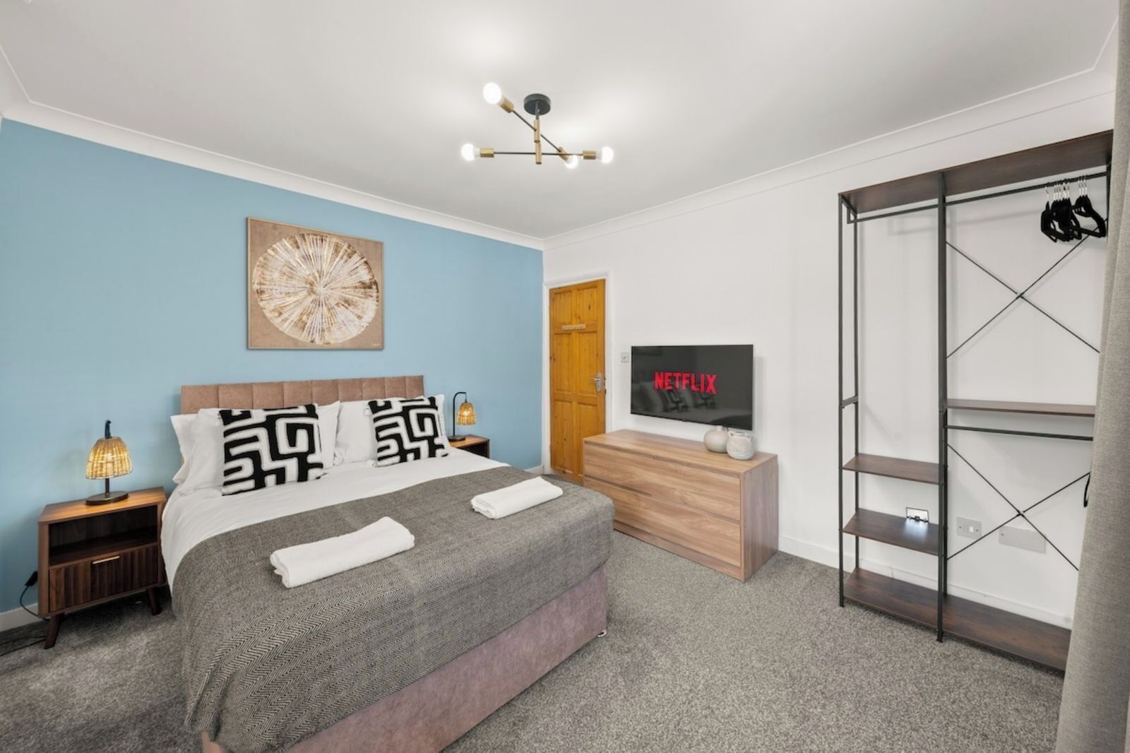 A modern bedroom with a bed, bedside lamps, a TV, and a wardrobe.