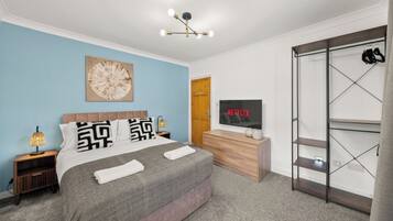 A modern bedroom with a bed, bedside lamps, a TV, and a wardrobe.