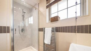 Ein modernes Badezimmer mit einer gläsernen Duschkabine, einer weißen Badewanne und einem Handtuchhalter.
