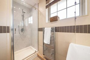 A modern bathroom with a glass-enclosed shower, a white bathtub, and a towel rack. - Spacious London House for Groups, Free Parking (Greater London)