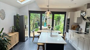 Una cucina moderna con isola centrale, pavimento scuro e vista su un giardino attraverso ampie finestre.