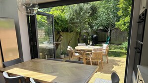 Una cucina moderna con un'ampia finestra, un'area pranzo con tavolo e sedie in legno, e vista sul giardino.