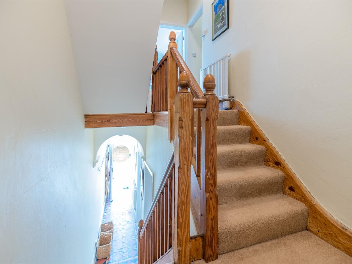 A carpeted staircase with wooden railings and a white wall.