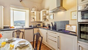 Una cucina con mobili bianchi, un forno a microonde, un tostapane e un fornello.