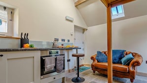 A kitchen with a built-in oven, a dining area with a high table, and a leather sofa. - 1 Bed in Whitby (oc-86298) (Castleton)