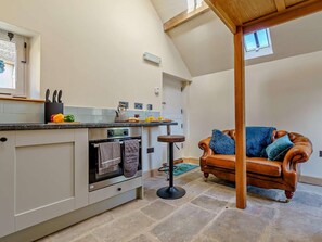 A kitchen with a built-in oven, a dining area with a high table, and a leather sofa. - 1 Bed in Whitby (oc-86298) (Castleton)