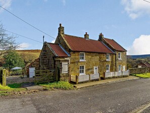 A stone house with a red-tiled roof, a wooden fence, and a gravel driveway. - 1 Bed in Whitby (oc-86298) (Castleton)