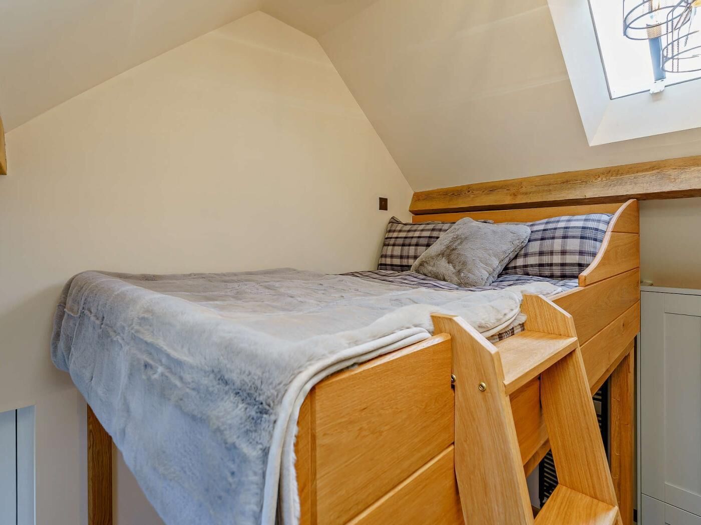 A loft-style bedroom with a wooden bunk bed, a skylight, and a view of the sky.