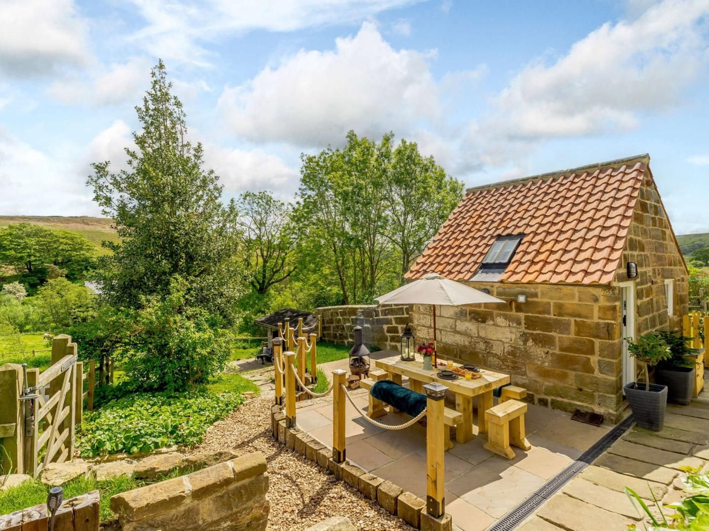 A stone building with a tiled roof, a wooden deck, and a table with outdoor seating.