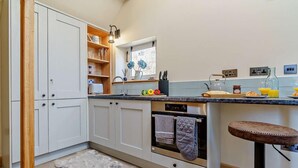 A kitchen with white cabinets, a built-in oven, a bar stool, and a window with flowers. - 1 Bed in Whitby (oc-86298) (Castleton)