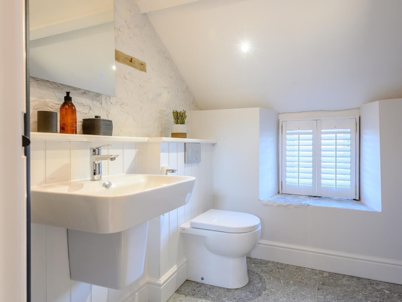 A bathroom with a white sink, toilet, and a window with blinds.