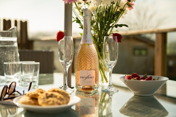 Eine Flasche Freixenet Italian Rosé Sekt, eine Schale Erdbeeren und ein Glas Wasser auf einem Tisch mit Blick.