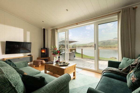 A living room with a TV, fireplace, and a view of a lake.
