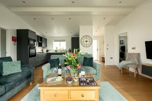 A modern living room with a sofa, coffee table, and a dining area with a clock on the wall.