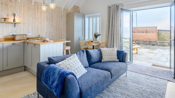 A modern interior with a kitchen, dining area, and a large window overlooking a patio. - 2 Bed in Bridgend (oc-86495) (Southerndown)