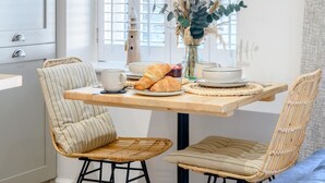 A dining area with a wooden table, two striped chairs, a vase with dried plants, and a croissant on the table. - 2 Bed in Bridgend (oc-86495) (Southerndown)