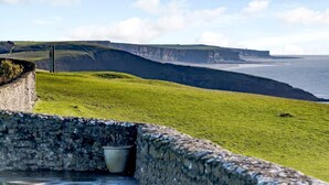 A coastal landscape with a stone wall, a grassy area, and a cliff overlooking the sea. - 2 Bed in Bridgend (oc-86495) (Southerndown)