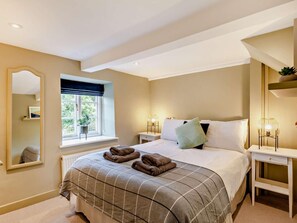 Une chambre à coucher avec un lit, des tables de chevet, une fenêtre avec des rideaux, un miroir et un radiateur.