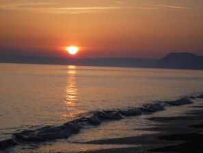 A sunset over a calm sea with gentle waves. - 3 Bed in Weymouth (oc-86474) (Langton Herring)