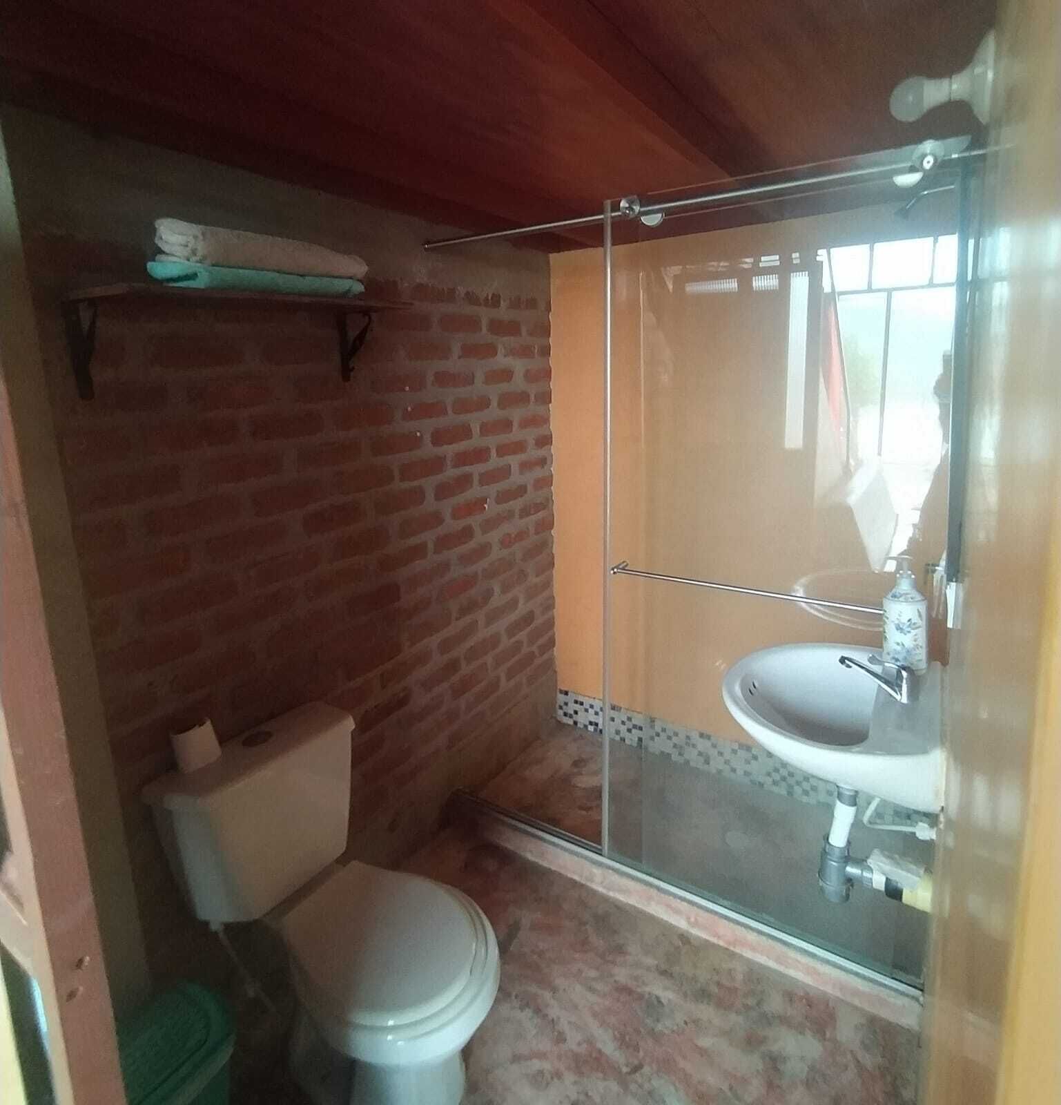 Un baño con inodoro, lavamanos y cabina de ducha.
