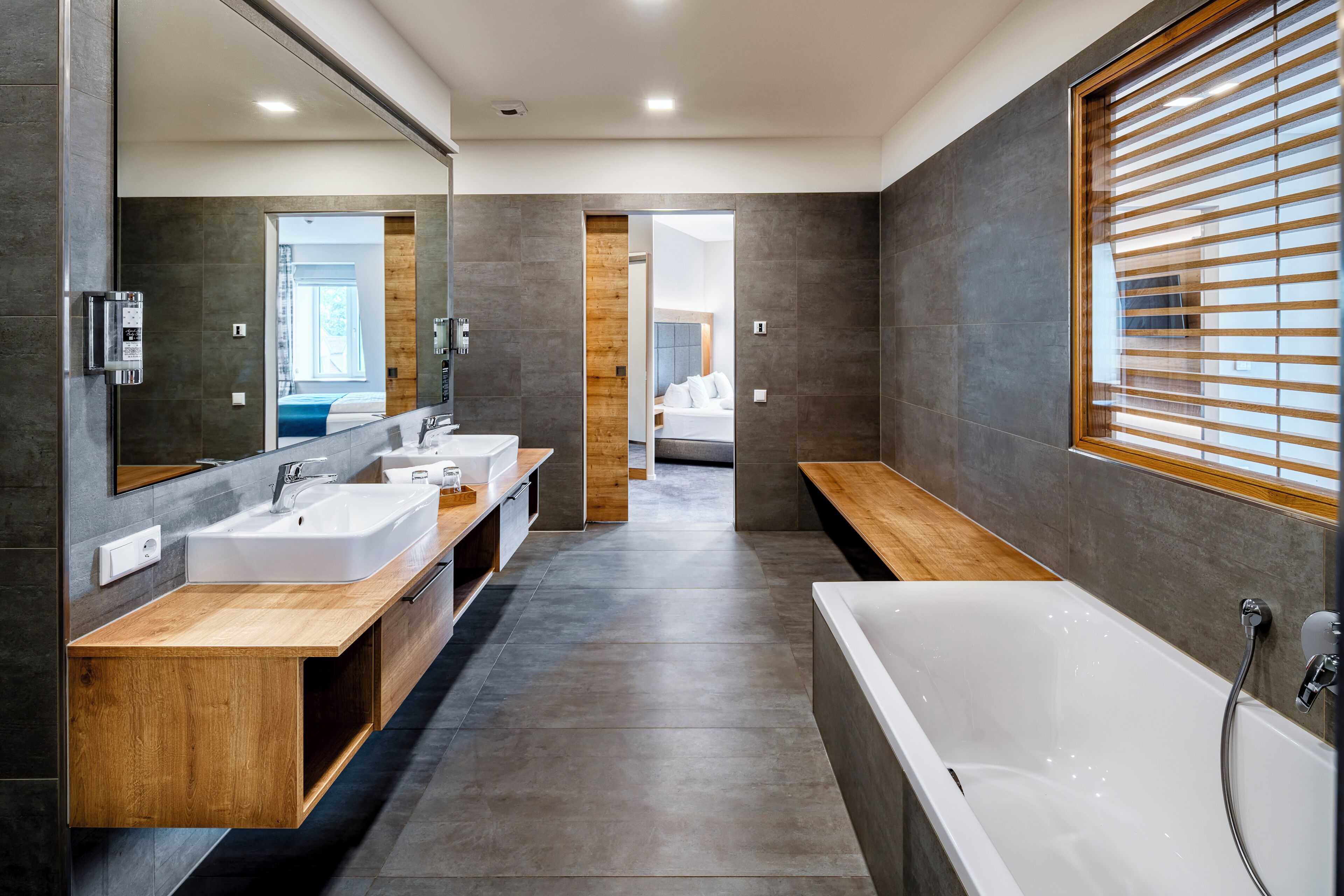 Un baño moderno con una bañera grande, dos lavabos y un mueble de tocador de madera.