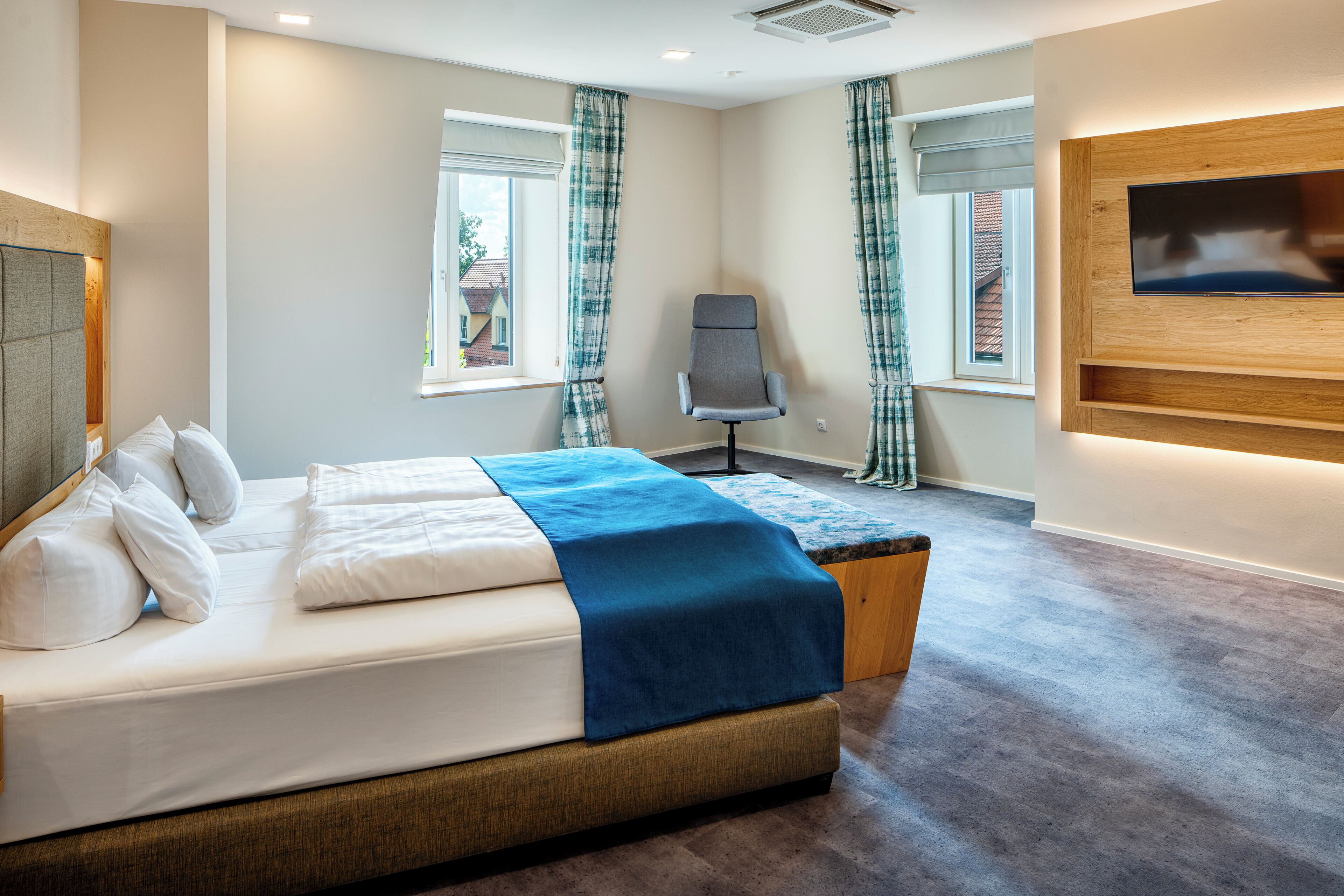 Une chambre d’hôtel équipée d’un lit, d’un bureau, d’une chaise et d’un téléviseur fixé au mur.