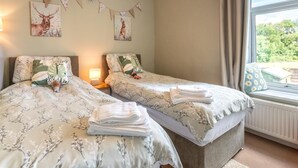 Une chambre avec deux lits, une fenêtre avec des rideaux et des éléments de décoration murale.