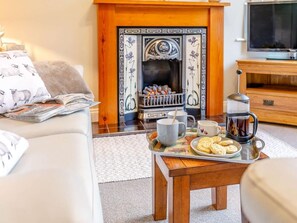 A cozy living room with a fireplace, a coffee table with cups and biscuits, and a sofa with a magazine. - 2 Bed in High Peak (oc-86413) (Whitehough)