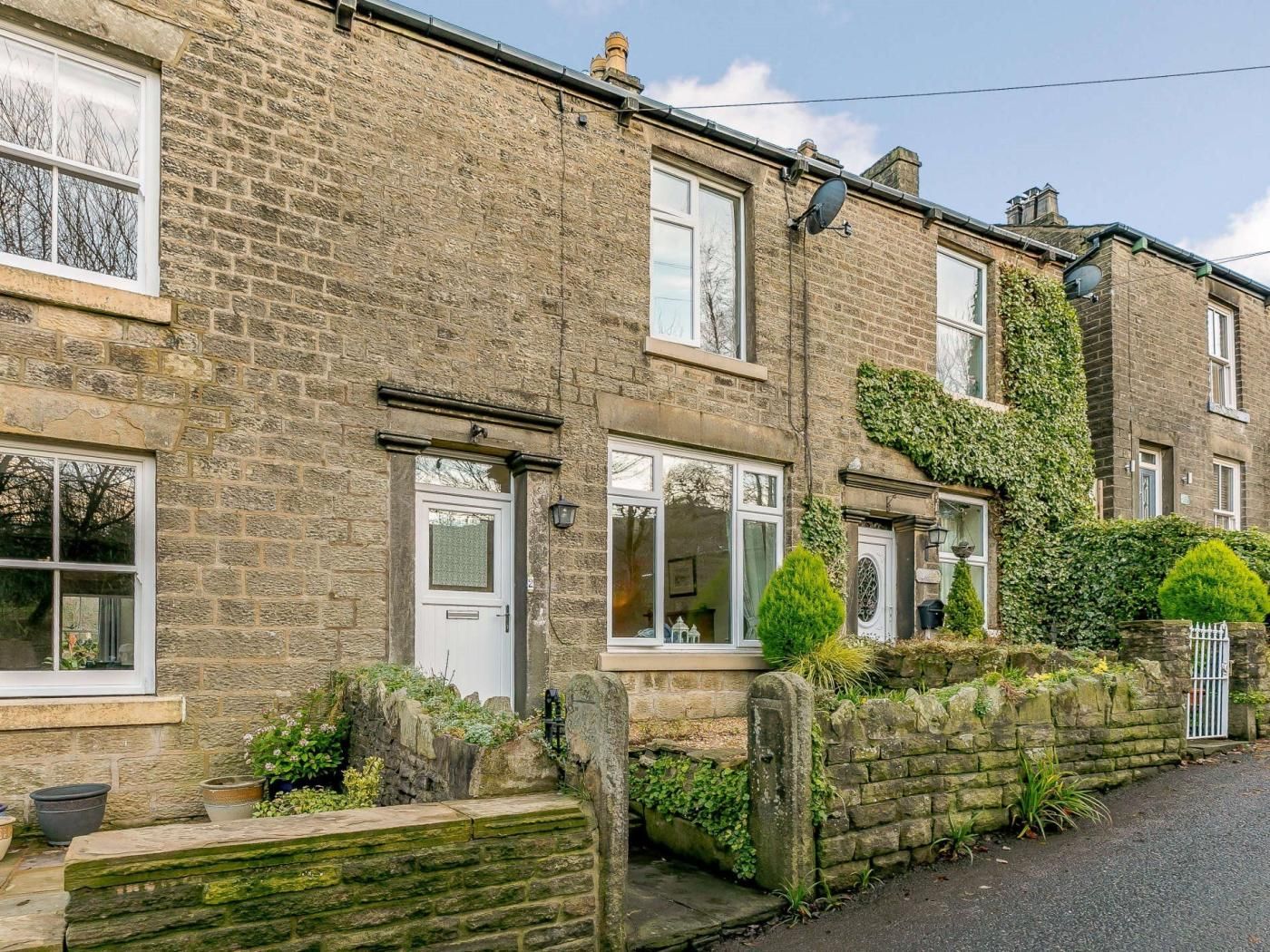 A row of terraced houses with stone walls, white doors, and windows.