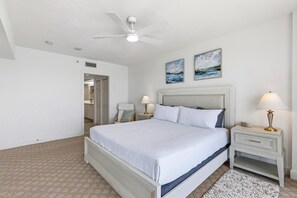 Ein Schlafzimmer mit einem Bett, Nachttischen, einem Deckenventilator und zwei Wandbildern.