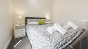 Ein ordentlich eingerichtetes Schlafzimmer mit einem Bett, zwei Nachttischen und einer Heizung.