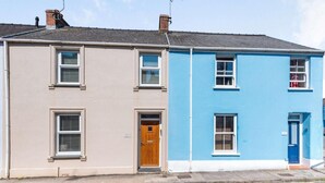 Ein zweistöckiges Gebäude mit einer beige- und blauen Fassade, einer Holztür und einem kleinen Vorbau.