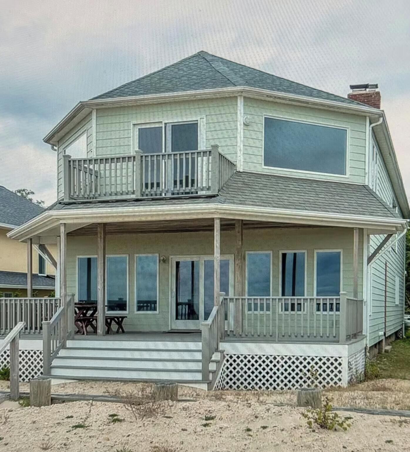 A two-story house with a balcony, a covered porch, and a staircase leading to the entrance.
