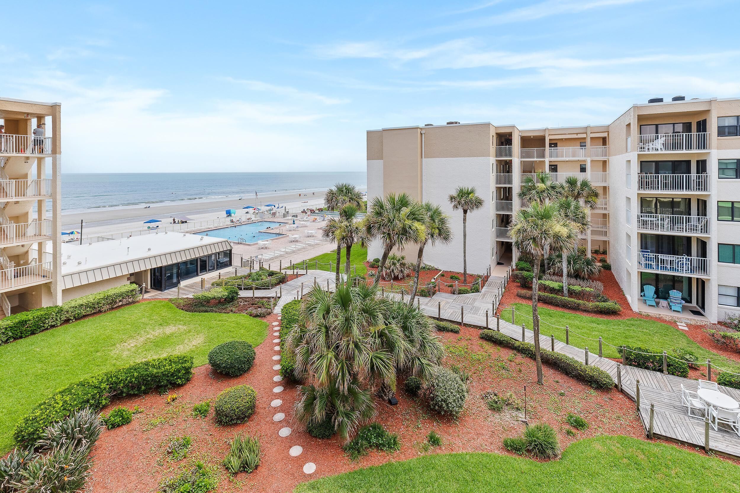 Un hotel con piscina, palme e vista sulla spiaggia.