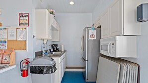 A compact kitchenette with a sink, a microwave, a refrigerator, and a fire extinguisher. - Castle Reef 407 (New Smyrna Beach)