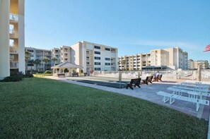 Un patio con césped, mobiliario exterior y un pabellón.